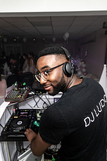 Image de dos, de Dj Ludo aux platines, fesant un sourir à l'objectif par dessus lépaule