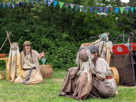 Kestrel storytelling holding Rheidol puppet while the other two puppets are held by musicians