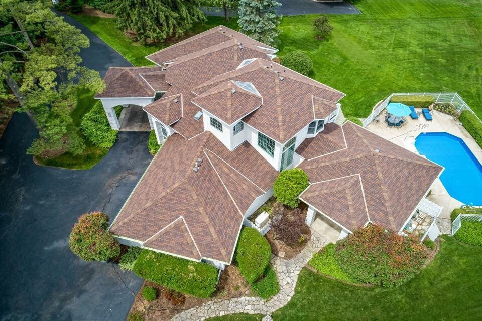 Aerial view of a large luxurious house with pool and green lawn.
