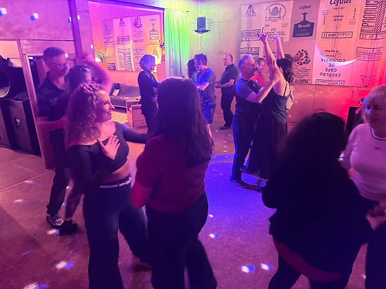 People dancing together at a Nelson Latin Dance social under colourful lights