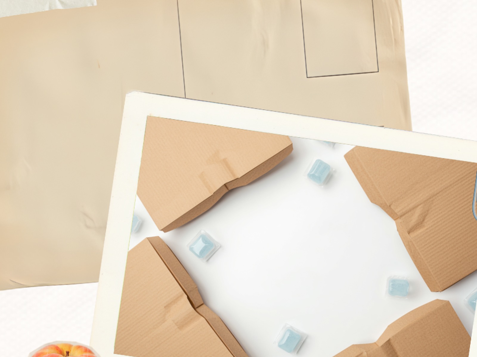 Overhead flat-lay of kraft recyclable paper thermal liners, soft cotton-style insulation panel, and blue gel packs on a clean studio surface
