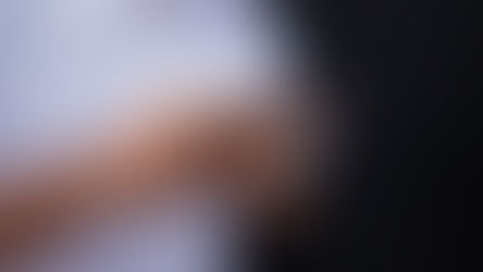 Person holding a smartphone in both hands while searching for information, photographed against a dark background
