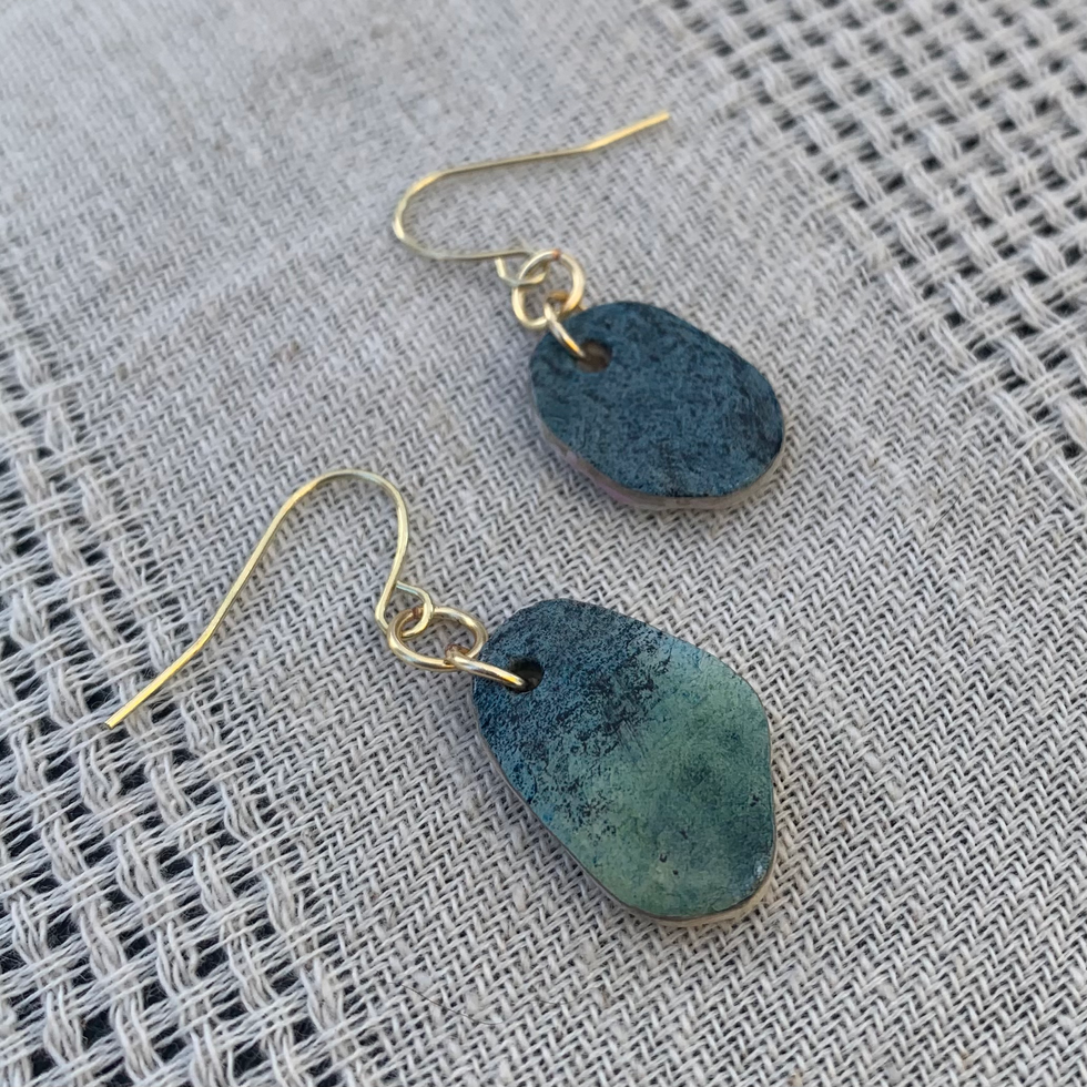 Photo of oval earrings made from seashell and paper, painted in blue and green tones, with gold.