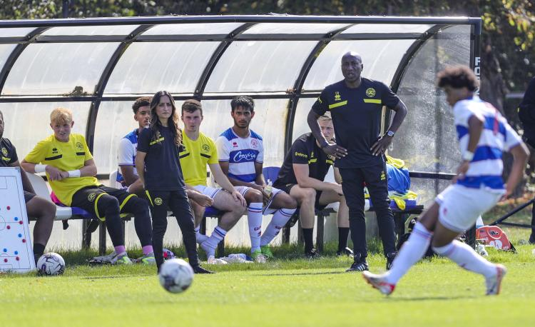 Young footballers participating in a football academy trial while coaches observe and assess player performance during a training session.
