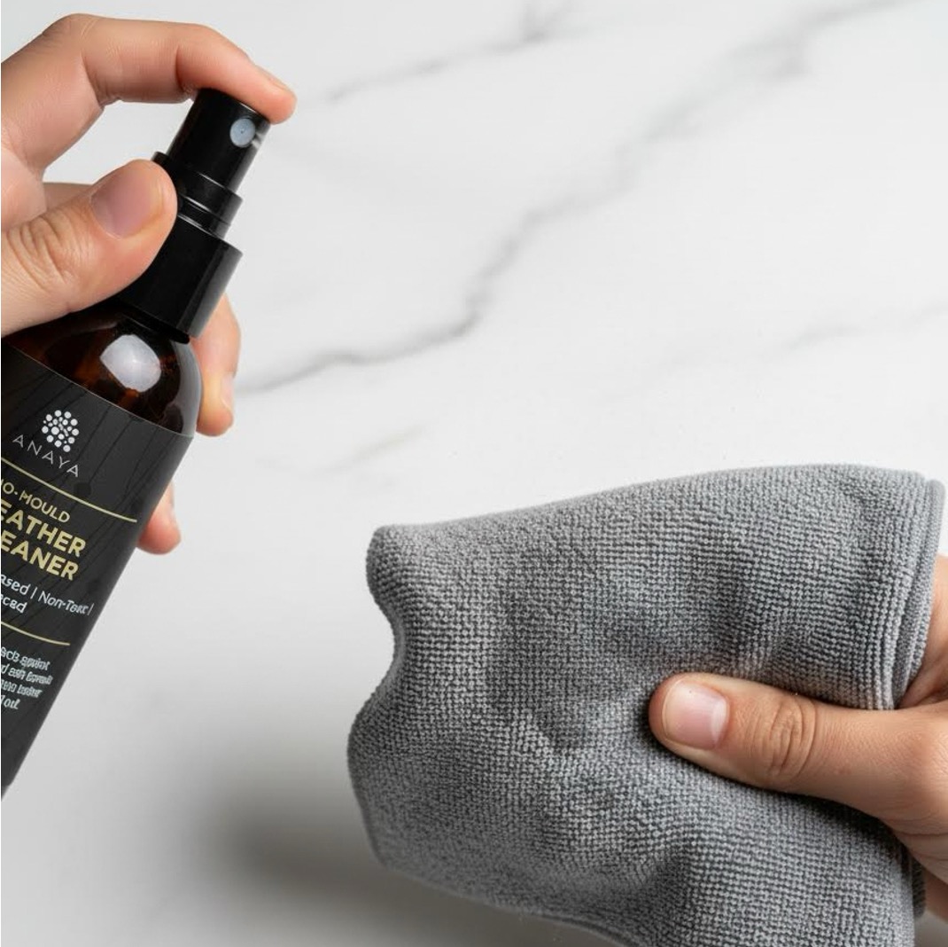 Spraying No-Mould Leather Cleaner onto a microfibre cloth rather than the bag