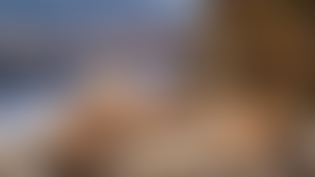 A serene Christmas scene overlooking a snowy Denver skyline, with wooden ornaments and wrapped gifts on a cozy table, capturing the magic of the season against the backdrop of majestic mountains.