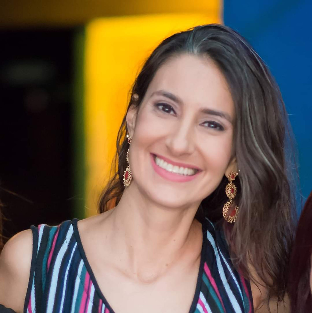 Bebel sorri para a foto, de blusa listrada colorida e brincos grandes e dourados