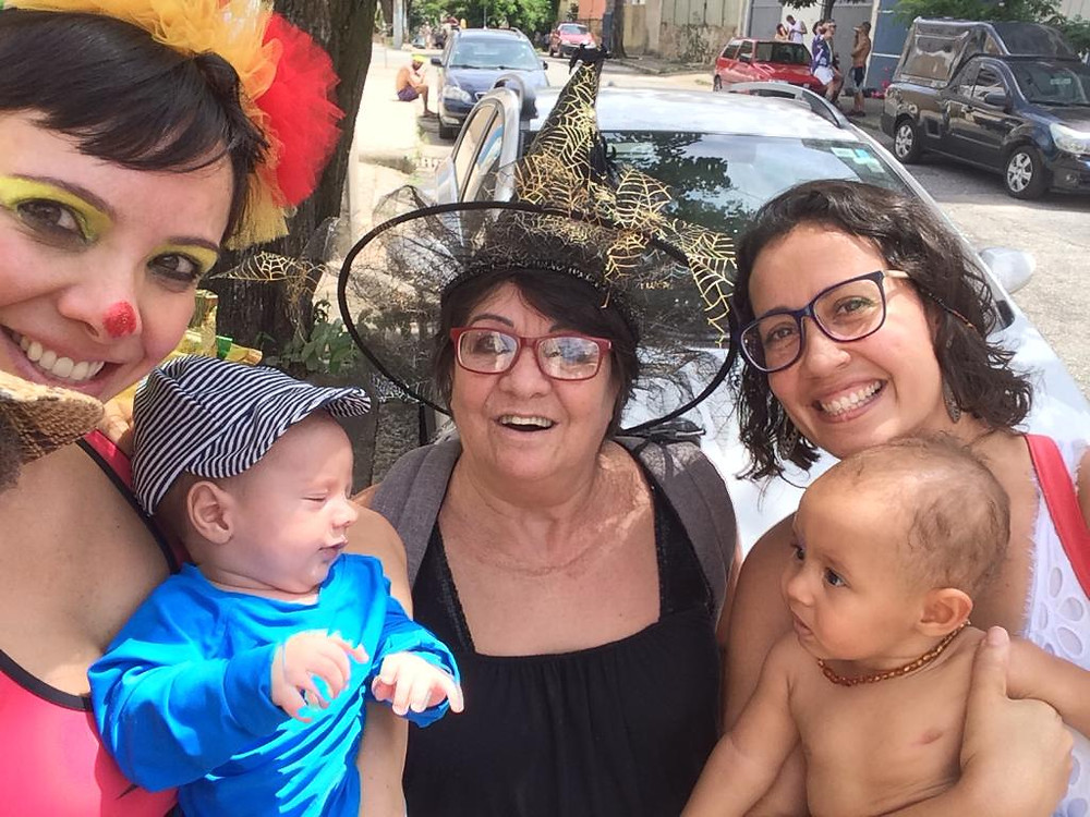 Cris aparece fantasiada, com Vicente no colo, ao lado de duas amigas, uma delas também segura um bebê
