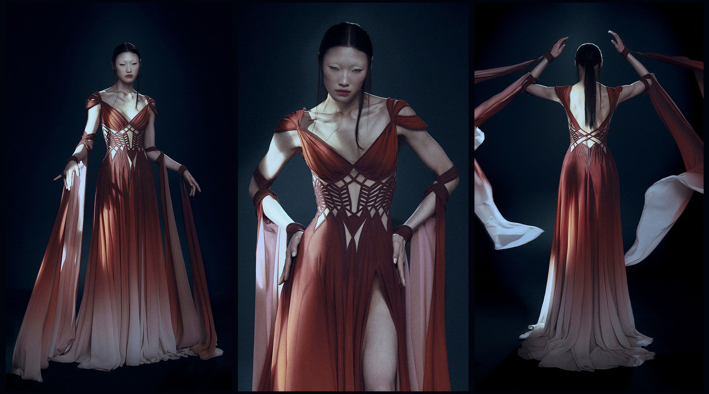 An Asian female model is wearing a Hassidriss open V-neck draped crepe dress, printed in a gradient from brick orange to oyster, featuring a leg slit and corseted gridded bandage work around her bare waist, with fabric cascading to the floor from her wrists.