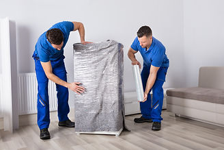 Two Young Male Movers Packing Furniture In Living Room.jpg