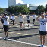 Young people practicing marching band formation, 'PRIDE OF COVE' on shirt.