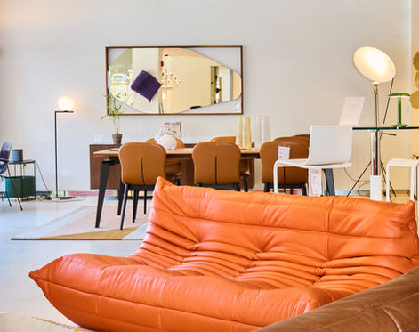 Dining room interior with orange sofa and modern pendant lighting.