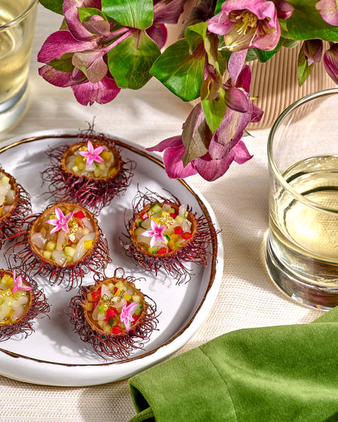Mini bite-sized appetizers on silver plate with flowers and green napkin in background captured by Washington DC food photographer Peggy Cormary