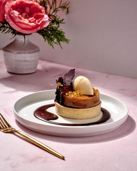 Elegant pear tart with scoop of ice cream and chocolate garnish on marble table captured by Washington DC food photographer Peggy Cormary.