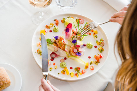 Gourmet dish with colorful garnishes and edible flowers on white plate.