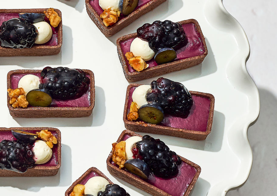 Blueberry-topped mini desserts arranged neatly on white plate.