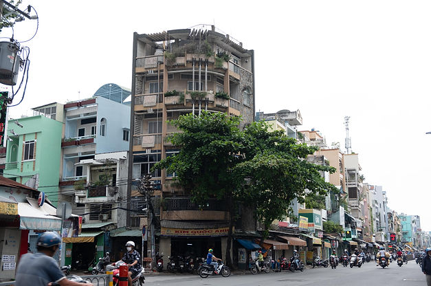 Saigon streetscape with narrow mid-century modernist townhouse covered in plants, highlighting everyday citizen-designed arch