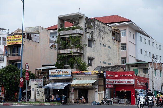Saigon streetscape with narrow mid-century modernist townhouse covered in plants, highlighting everyday citizen-designed architecture and organic evolution of Vietnamese modernism