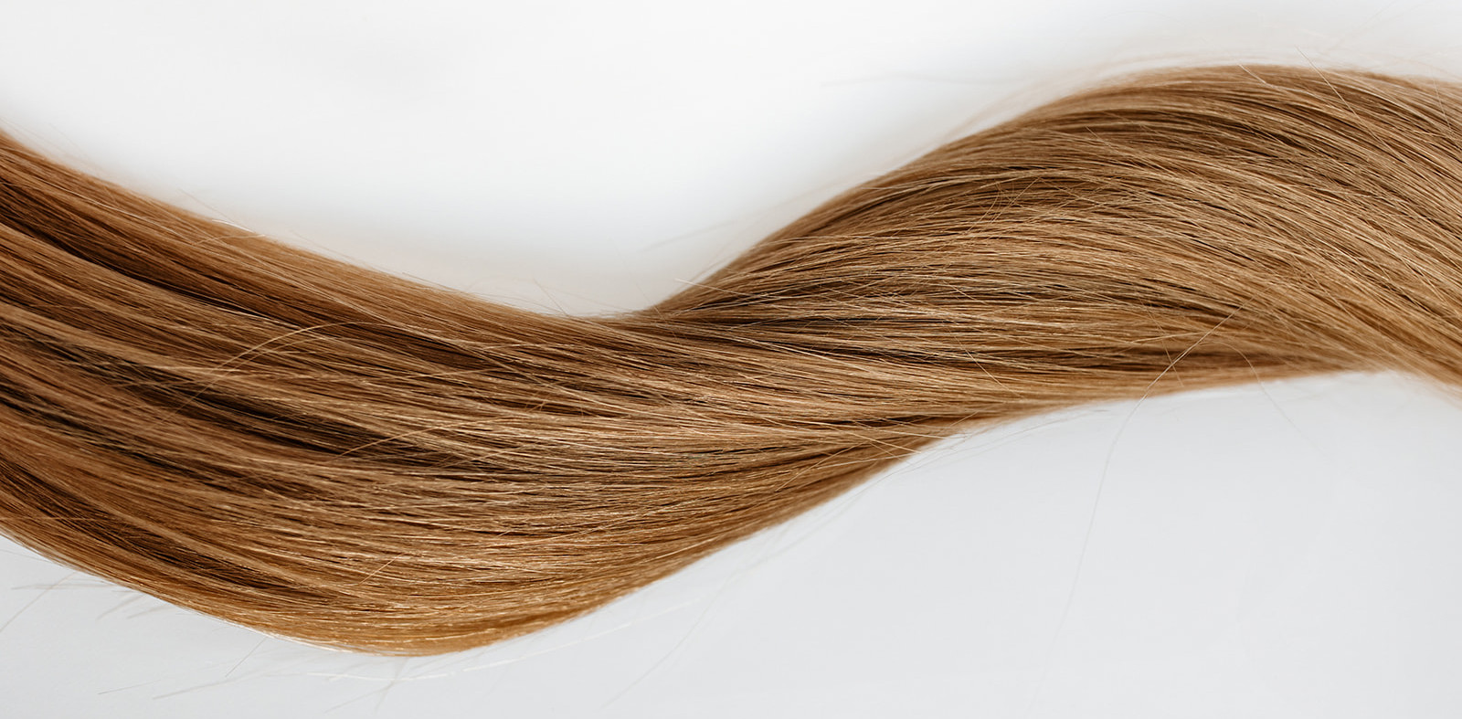 Close-up of smooth brown hair strands curving across a white background, creating a sleek, flowing texture.