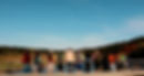 12 young people with backpacks looking out over a bridge on the Camino de Santiago in Spain. A unicycle leans against the wall on the left side.