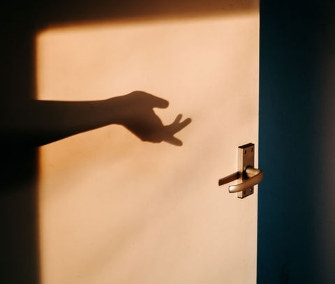 Shadow of a hand reaching for a door handle