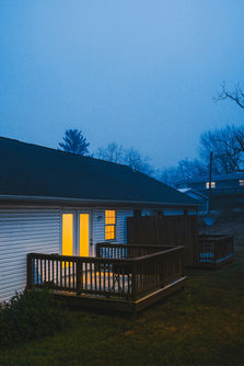House with glowing doors and deck on a misty night