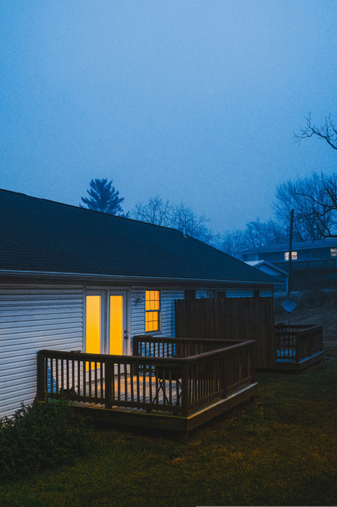 House with glowing doors and deck on a misty night