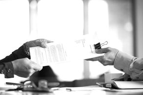 Manos intercambiando un contrato o acuerdo impreso sobre un escritorio, parte del proceso de habilitación de un local comercial en Chile