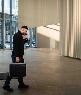 Alexa läuft telefonierend durch das Foyer eines Gebäudes – Werkzeugkoffer in der rechten Hand, Symbolbild für 24/7-Notdienst