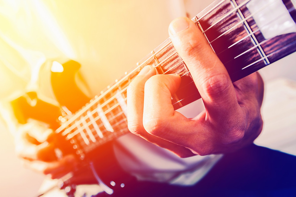 A man playing a chord on the guitar