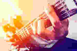 A man playing a chord on the guitar