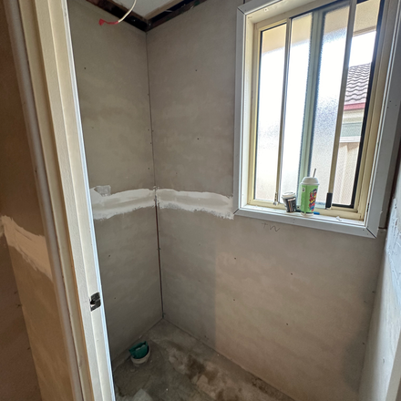 a corner of a room with a window and a bottle of glue on the window sill