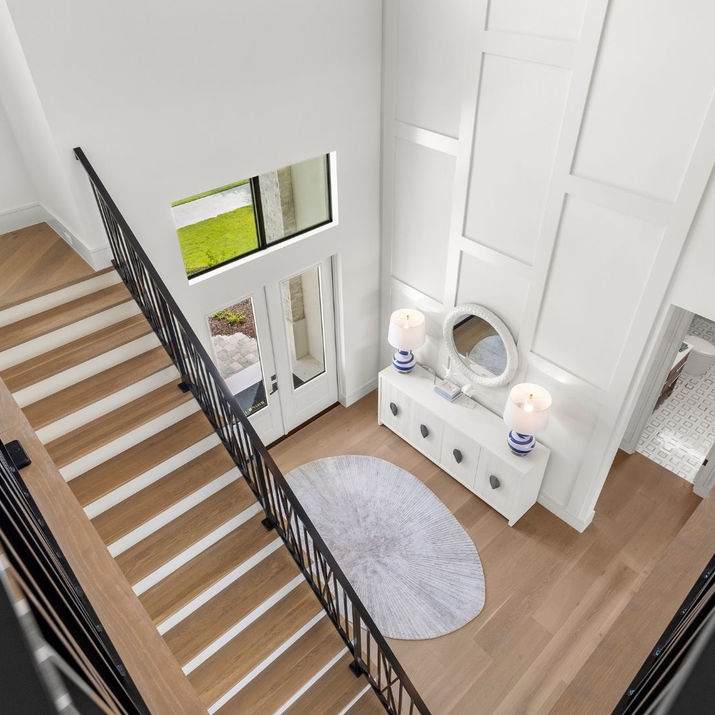 Modern entryway with high ceilings and wooden stairs