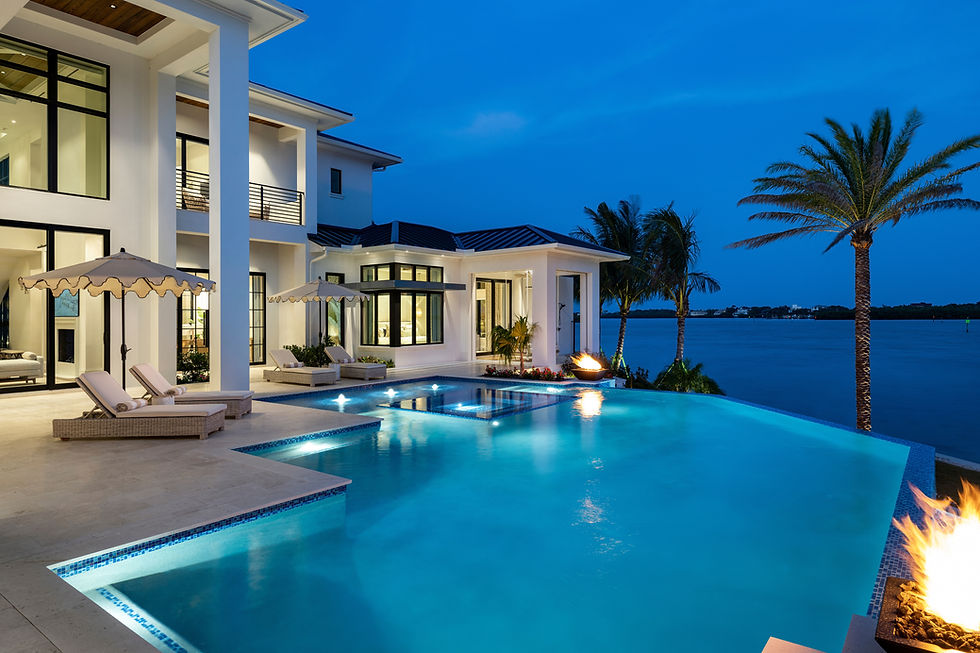 Modern luxury waterfront home with infinity pool at dusk