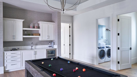 Modern game room with a pool table, wet bar, and laundry access.