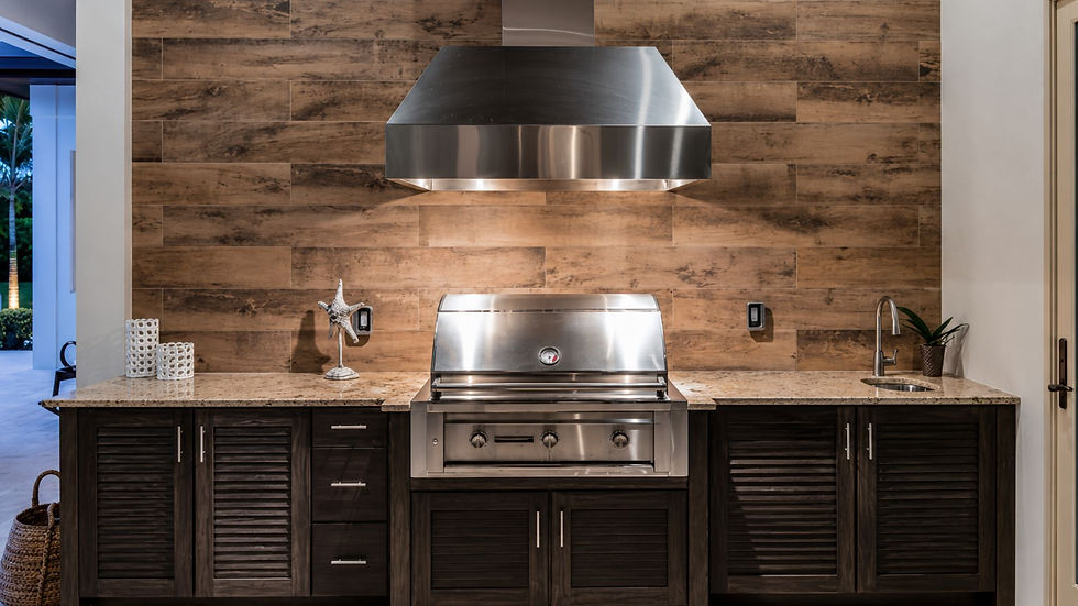 Outdoor kitchen with stainless grill and hood, wood-look backsplash, stone counters, and dark cabinets