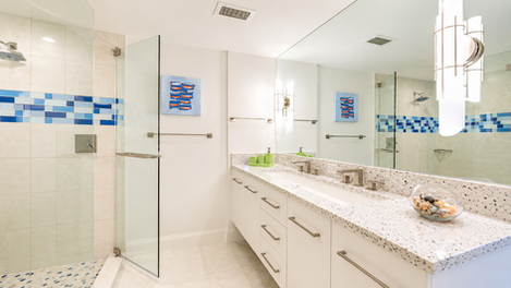 Modern white bathroom with glass shower and double vanity.