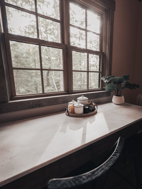 Marble surface desk set next to a window with a tea tray and potted plant, featuring natural light pouring through. Ellijay, GA Reynard Architectural Designs