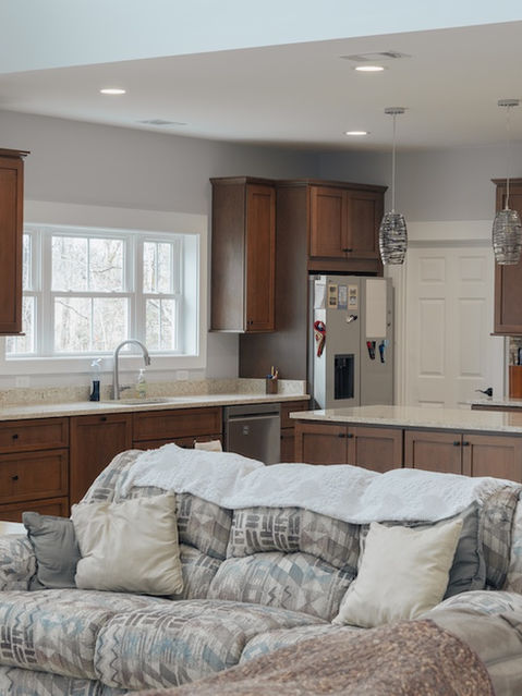 Open concept living room looking into a spacious kitchen with dark wood cabinets, a large island with open shelving, and stainless steel appliances. Custom Home Architecture by James Knight. Photos by Kalyn Kight
