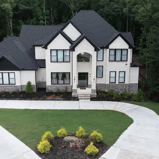 Modern transitional custom home exterior with a white brick facade, sharp black trim, steep gables, and a grand arched entryway designed by Reynard Architectural Designs in Lawrenceville, GA.
