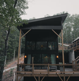 RIVERTOP home by Reynard Custom Homes, showcasing the home’s unique placement above the river, surrounded by mature trees and natural landscaping. The design emphasizes privacy, connection to the landscape, and unobstructed river views. Architectural designs by James Knight of Reynard Custom Homes. 