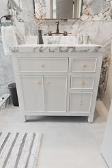 Luxury custom bathroom design featuring a white fluted single vanity, marble countertops, a black-framed mirror, and dramatic gray marble wall tiles.