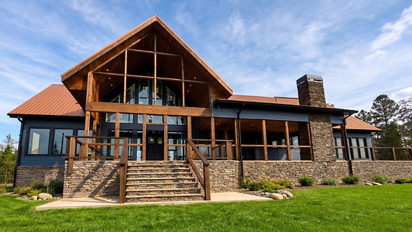 Rear view of the custom mountain home designed by James Knight of Reynard Architectural Designs with a stairway, stacked stone and chimney with copper roofing and timber framing on the outside with a wraparound porch in Talking Rock, GA. Architecture by Reynard Architectural Designs and construction by Bluedog Construction.