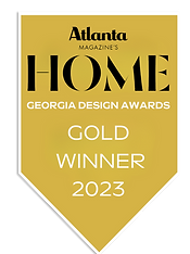 A gold, banner-shaped award badge. The top features the logo for "Atlanta Magazine's HOME" in black serif text. Below, white sans-serif text reads "Georgia Design Awards," followed by "GOLD WINNER 2024" in large capital letters. Reynard Custom Homes Architecture