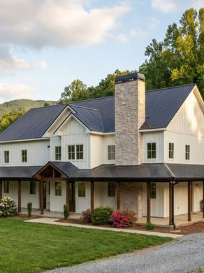 Exterior view of a custom two-story home in Hiawassee, GA, designed by James Knight of Reynard Custom Homes. The house features light-colored horizontal siding, a prominent stone chimney, and a wide covered front porch with natural wood columns.