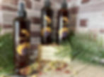 Thumbnail: amber spray bottle with leave in conditioner in it surrounded by roses and jasmine on a wood stand with green leaves.