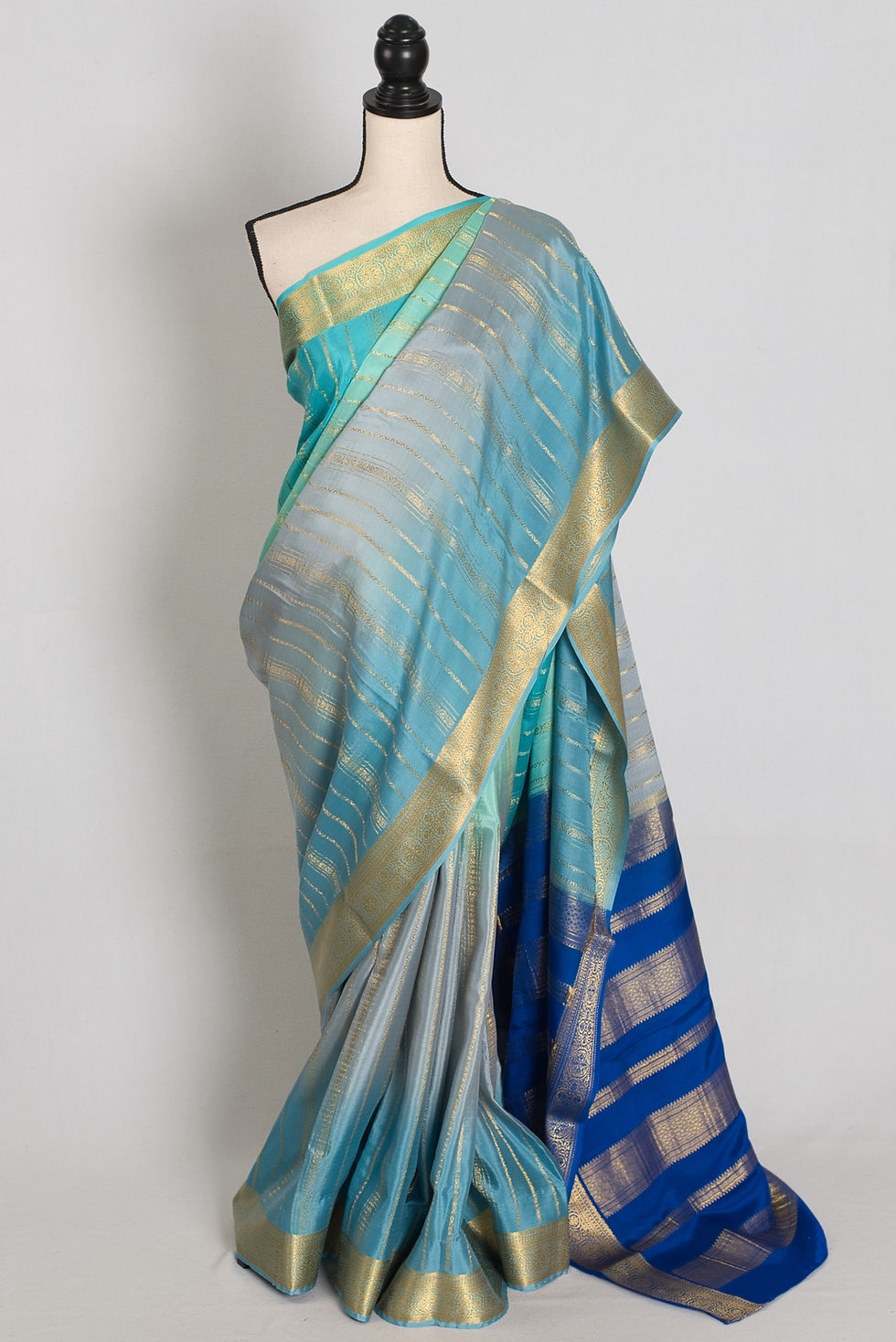 Thumbnail: Grey and blue shaded Mysore crepe silk saree with vertical gold zari stripes draped in a mannequin.