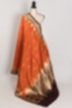 Bina rust orange and coffee brown handwoven Banarasi silk saree with golden zari temple border on a mannequin.