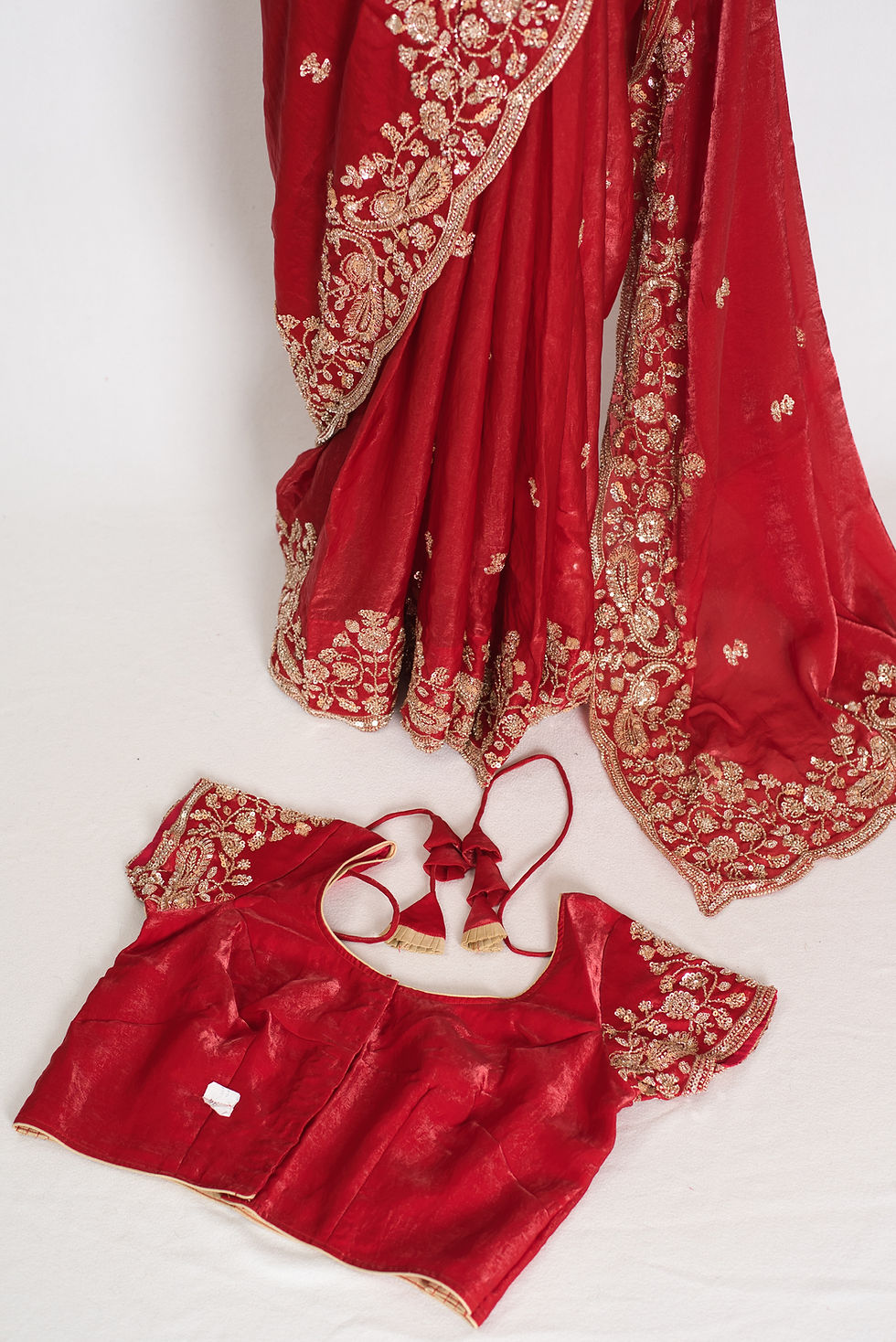 Front view of the bright red tissue zardosi embroidery saree draped on a mannequin with blouse.