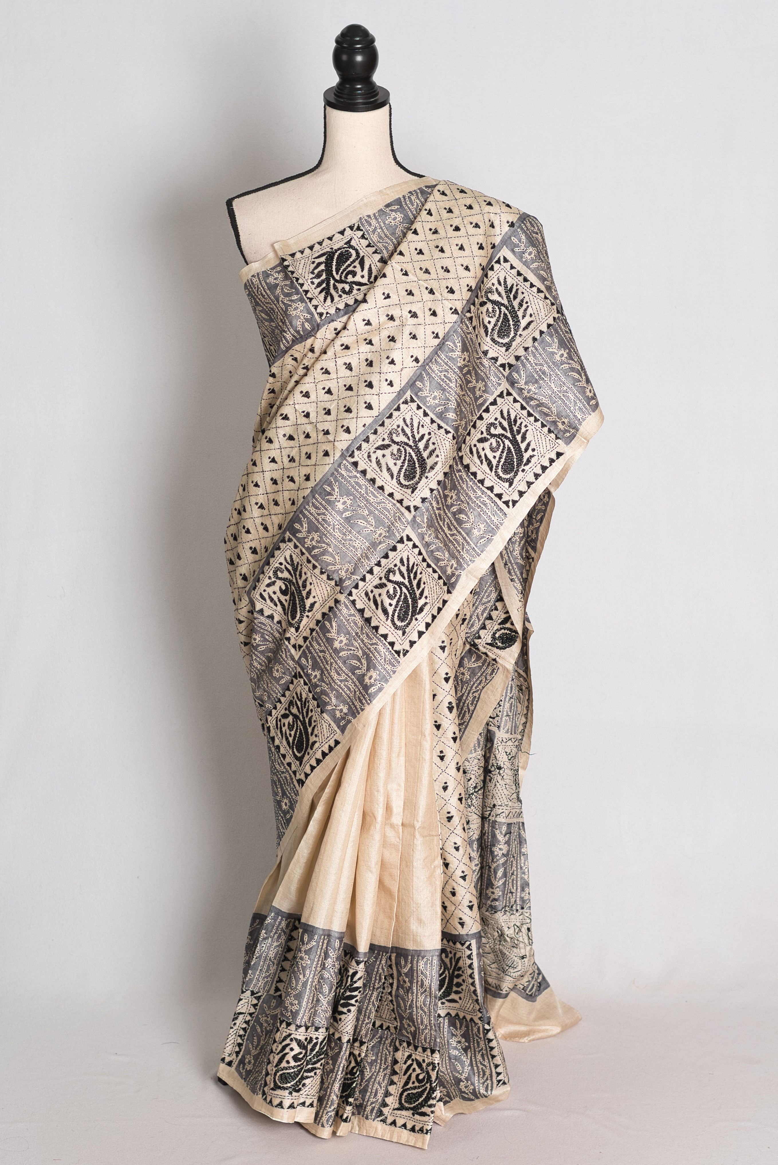 Beige Kantha Stitch Gachi Tussar Silk Saree draped on a mannequin highlighting its unique printed and black embroidered pallu